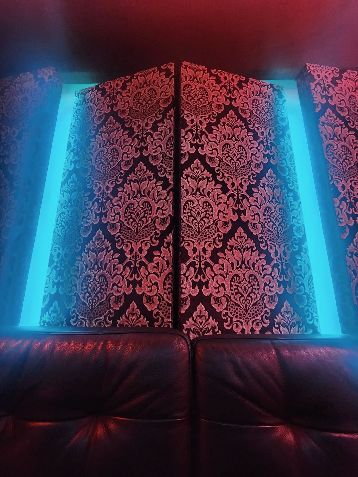 SonikBox leather lounge seating against backlit damask-patterned acoustic wall panels.